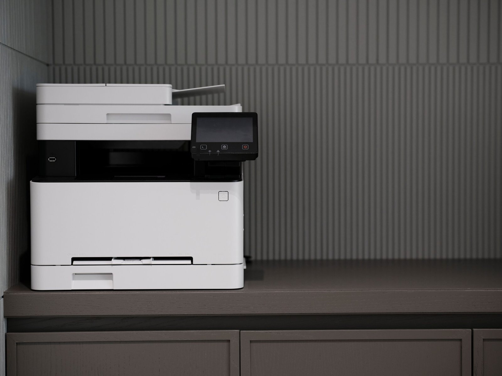 A sleek, modern printer situated on a minimalist office desk with a textured background.